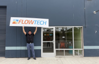 FlowTech founder and president Zach Liske holds company sign at Santa Cruz office